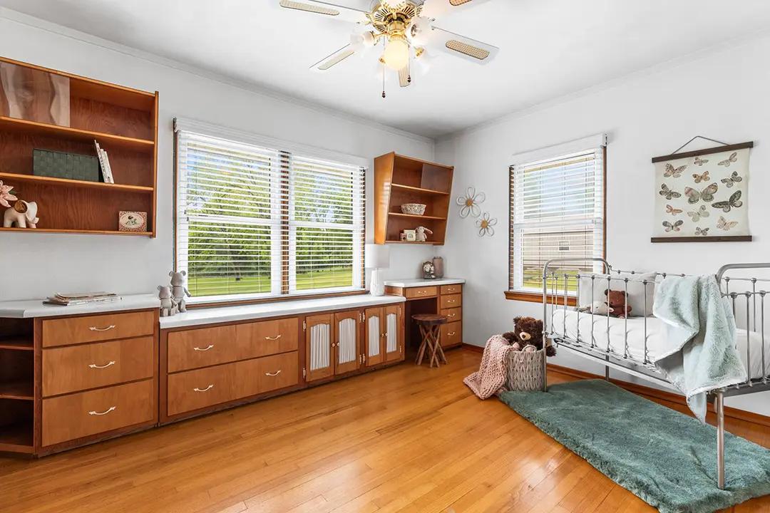 Bright bedroom with built-in wood storage, hardwood floors, and a metal bed frame