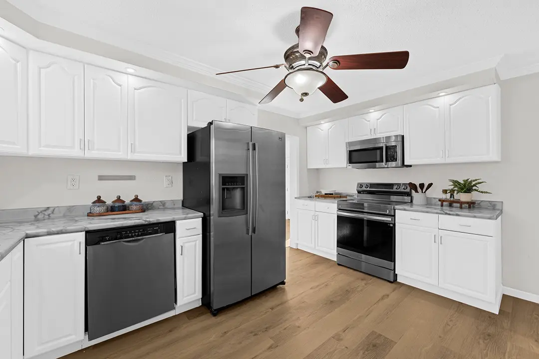 Updated white kitchen with stainless steel appliances, gray countertops, and wood flooring